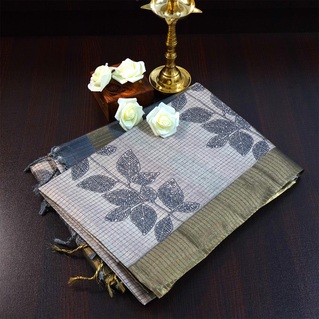 Harini Tussar in soft beige-grey base with a subtle checked pattern, beautifully accented by dark charcoal leaf motifs