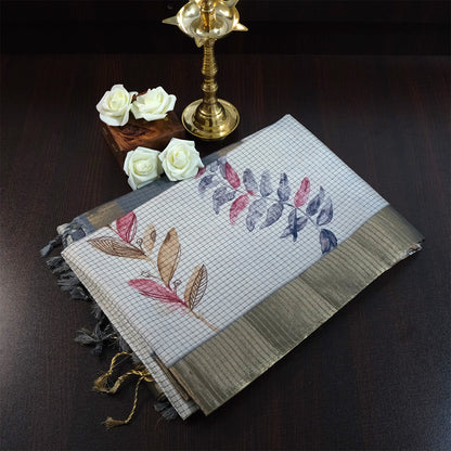 Harini Tussar in soft off-white base with multicolored leaf motifs in shades of pink, blue, and brown, beautifully complemented by an elegant metallic grey border.