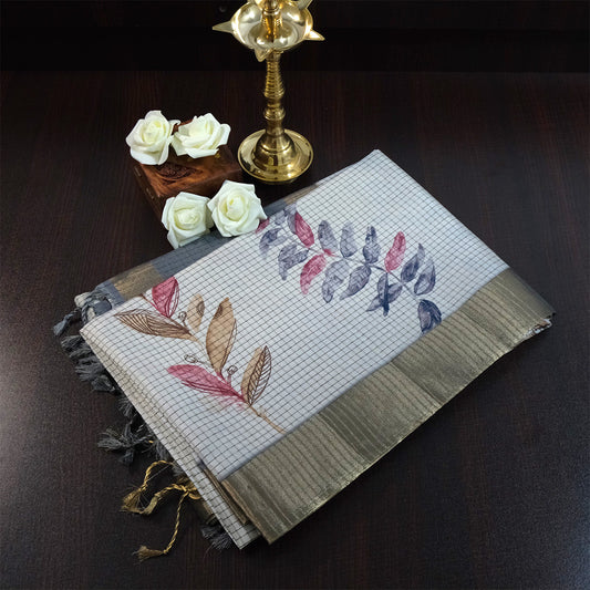 Harini Tussar in soft off-white base with multicolored leaf motifs in shades of pink, blue, and brown, beautifully complemented by an elegant metallic grey border.