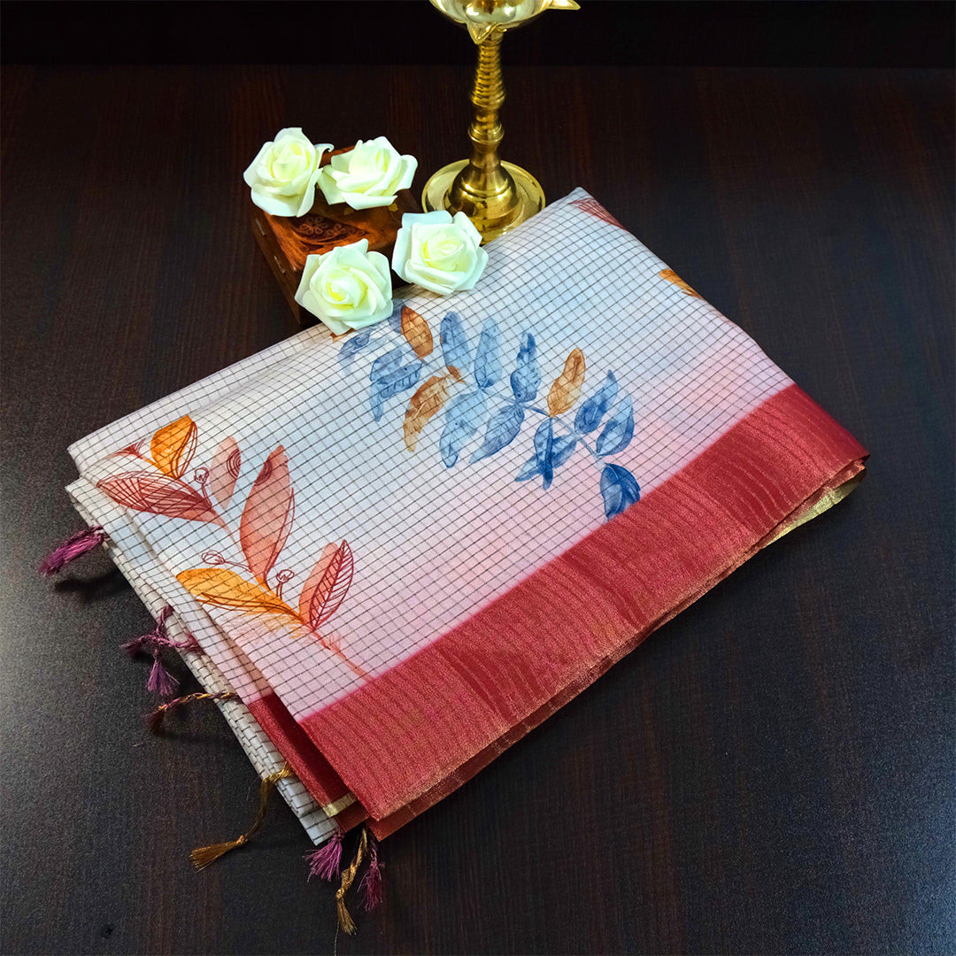 Harini Tussar in soft white base with colorful leaf motifs in blue, orange, and mustard, complemented by a rich maroon border.