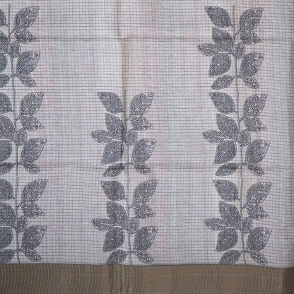Harini Tussar in soft off-white base with multicolored leaf motifs in shades of pink, blue, and brown, beautifully complemented by an elegant metallic grey border.