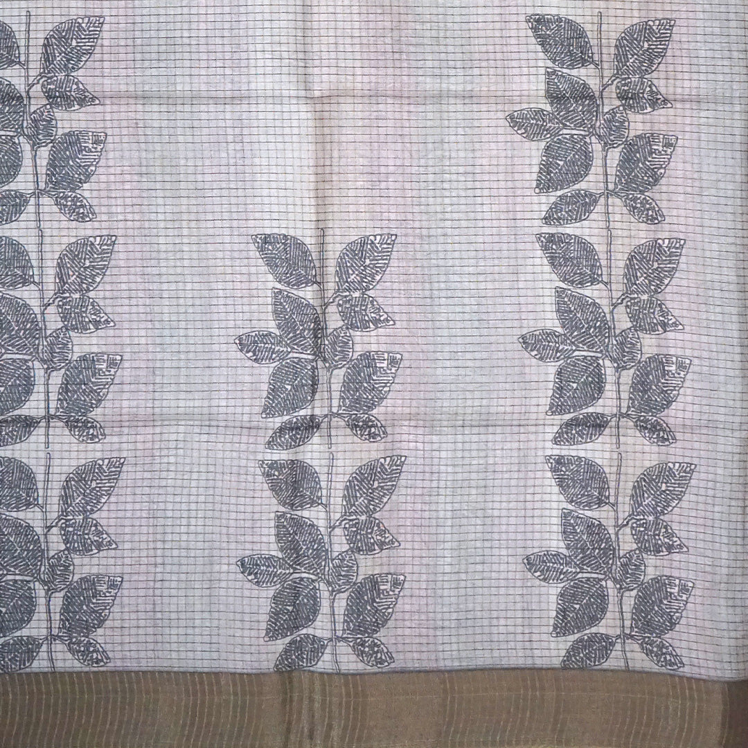 Harini Tussar in soft beige-grey base with a subtle checked pattern, beautifully accented by dark charcoal leaf motifs