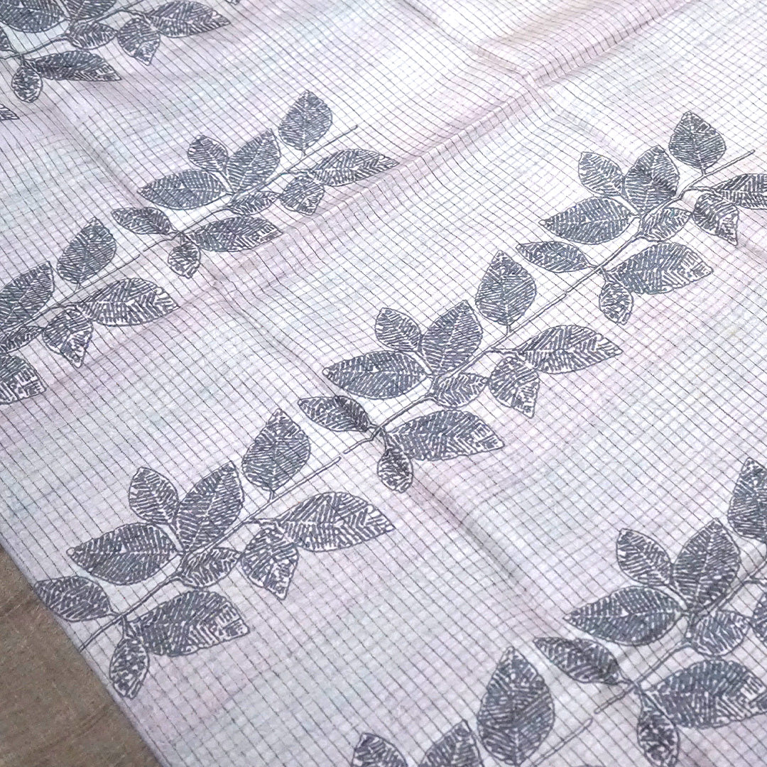 Harini Tussar in soft off-white base with multicolored leaf motifs in shades of pink, blue, and brown, beautifully complemented by an elegant metallic grey border.
