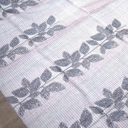 Harini Tussar in soft off-white base with multicolored leaf motifs in shades of pink, blue, and brown, beautifully complemented by an elegant metallic grey border.