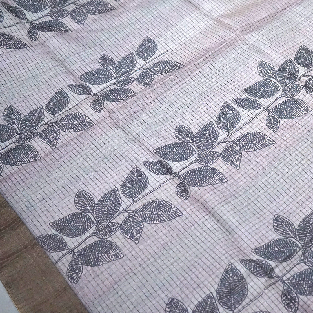 Harini Tussar in soft beige-grey base with a subtle checked pattern, beautifully accented by dark charcoal leaf motifs
