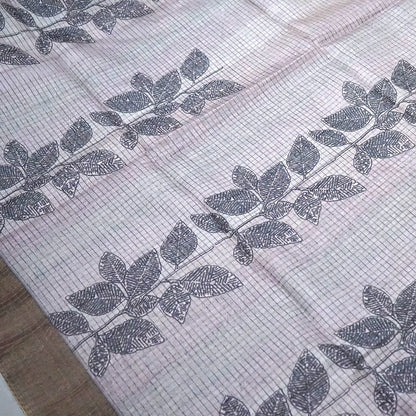Harini Tussar in soft beige-grey base with a subtle checked pattern, beautifully accented by dark charcoal leaf motifs
