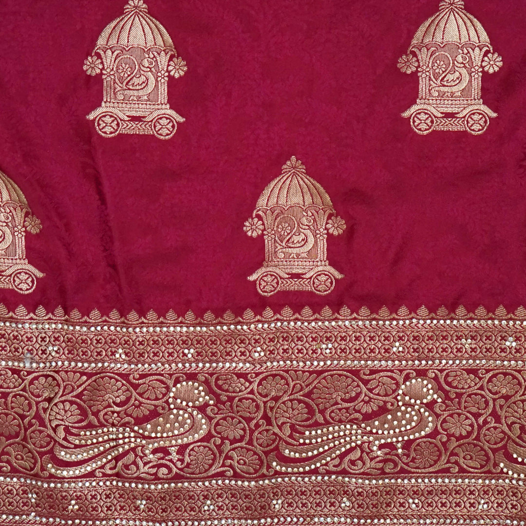 Royal Ratha Banarasi silk in deep maroon red shade, highlighted with rich golden zari motifs and an ornate golden border.