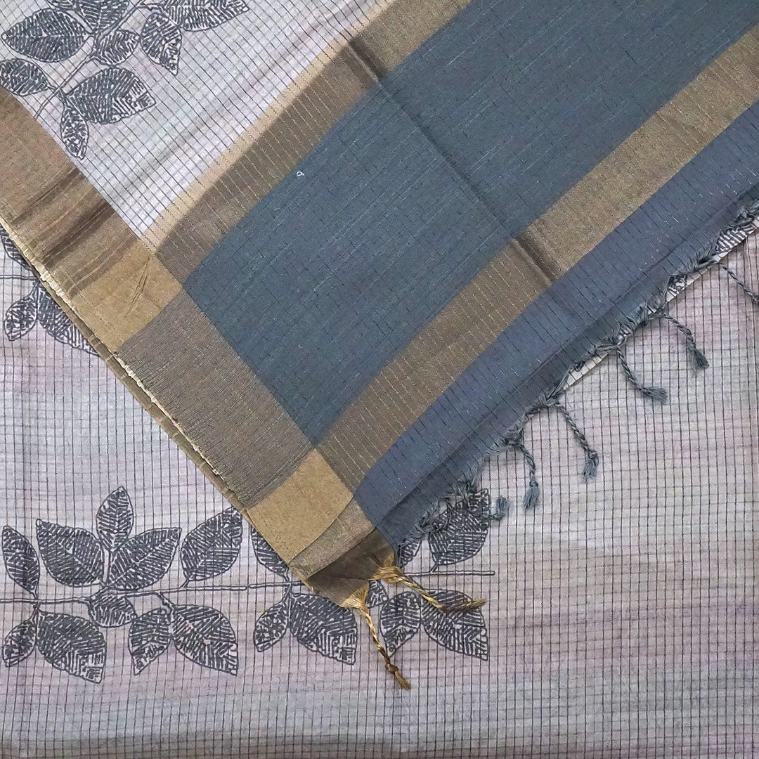 Harini Tussar in soft beige-grey base with a subtle checked pattern, beautifully accented by dark charcoal leaf motifs