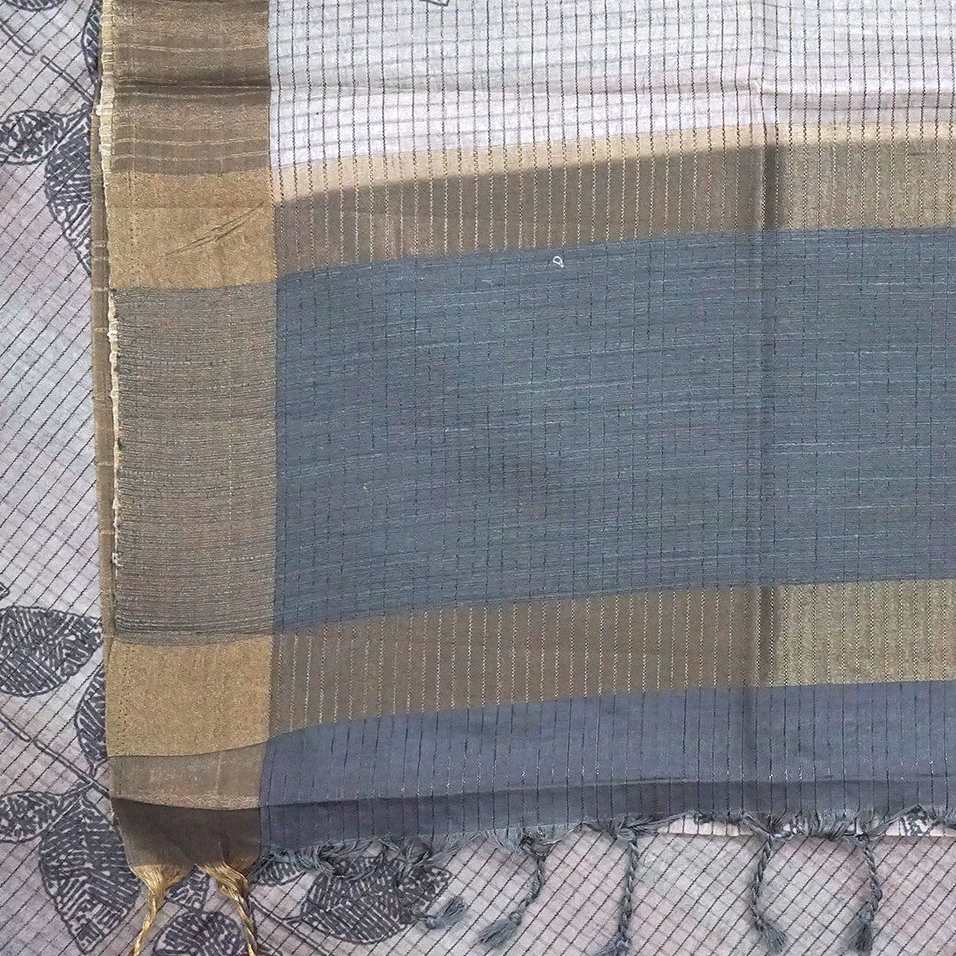 Harini Tussar in soft off-white base with multicolored leaf motifs in shades of pink, blue, and brown, beautifully complemented by an elegant metallic grey border.
