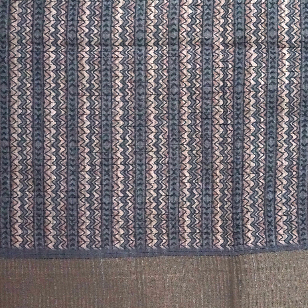 Harini Tussar in soft off-white base with multicolored leaf motifs in shades of pink, blue, and brown, beautifully complemented by an elegant metallic grey border.