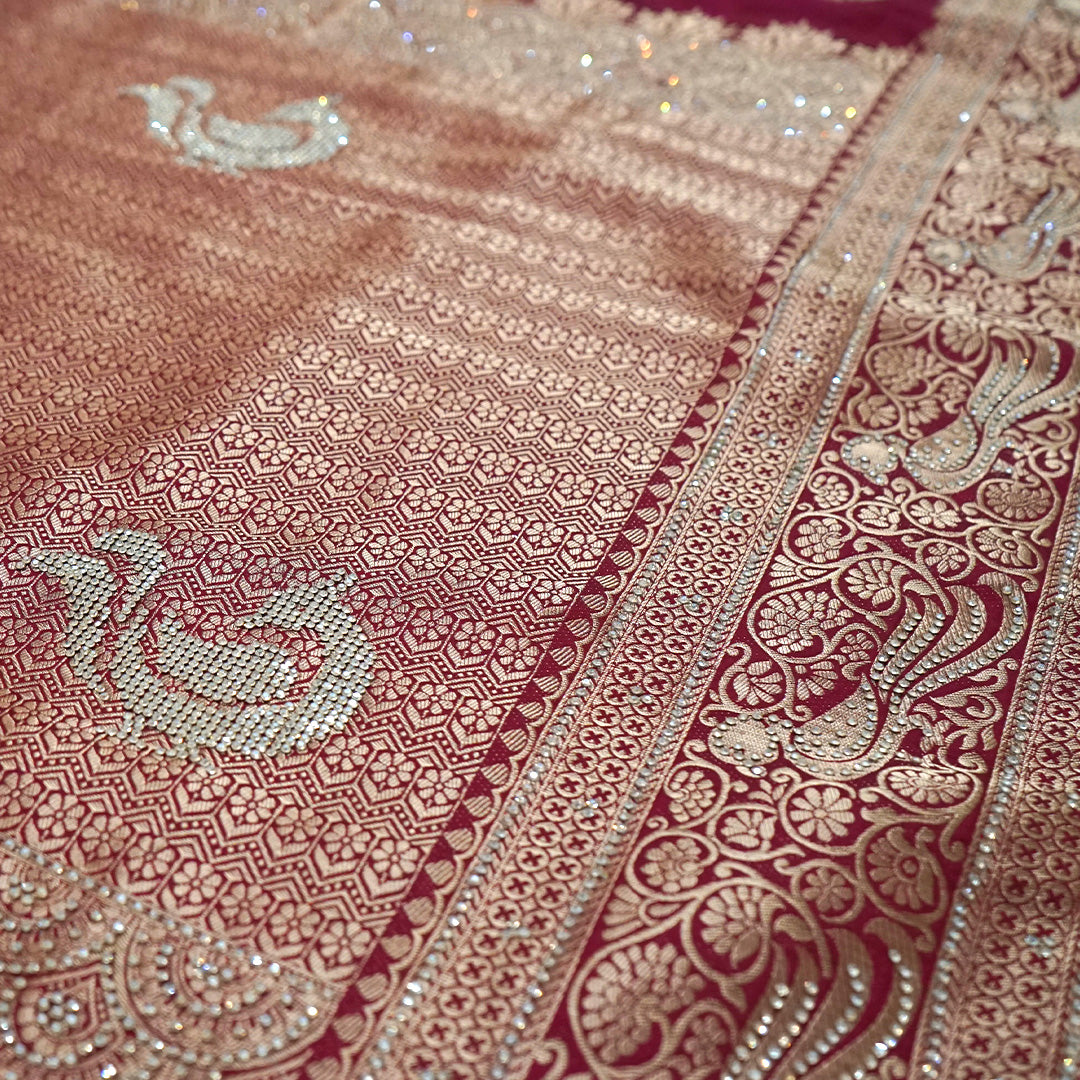 Royal Ratha Banarasi silk in deep maroon red shade, highlighted with rich golden zari motifs and an ornate golden border.