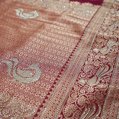 Royal Ratha Banarasi silk in deep maroon red shade, highlighted with rich golden zari motifs and an ornate golden border.