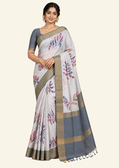 Harini Tussar in soft off-white base with multicolored leaf motifs in shades of pink, blue, and brown, beautifully complemented by an elegant metallic grey border.